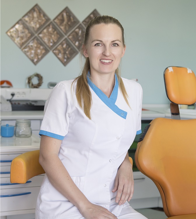 Portrait image of the dental surgeon, Tatiana Fragou, sitting in her surgery.