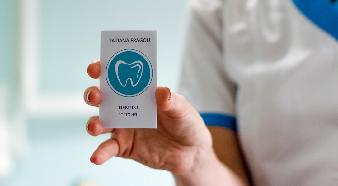 An image of Tatiana Fragou (dental surgeon) holding up her business card.